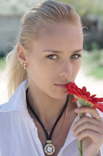 Girl in white biting a red flower.