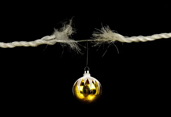 Frayed rope with christmas bulb holiday stress concept isolated on black background