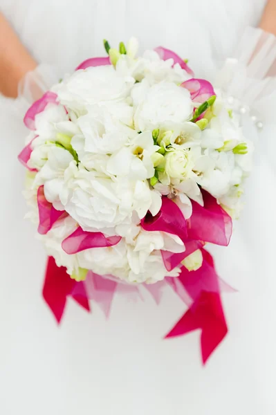 Wedding bouquet with white flowers in hands of bride