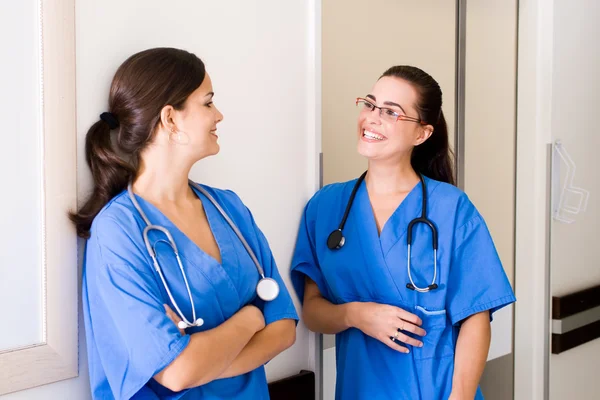 :two happy young medical nurses talking to each other during break