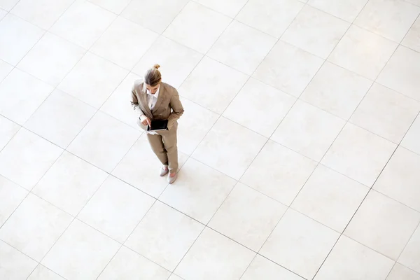 Overhead view of young businesswoman using tablet computer while standing on lobby