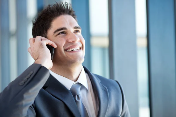 Happy young businessman talking on the mobile phone