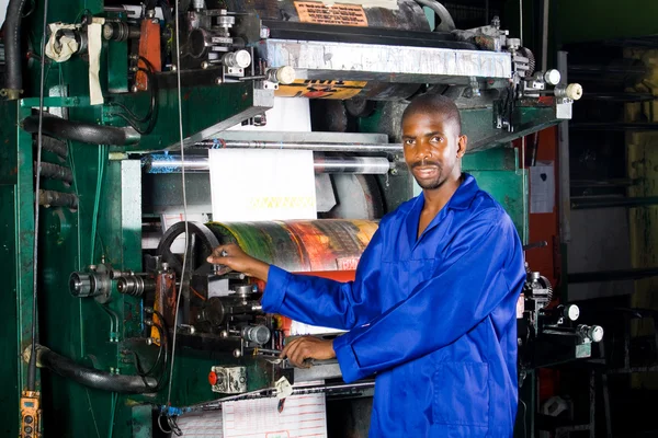 African printing press operator in factory