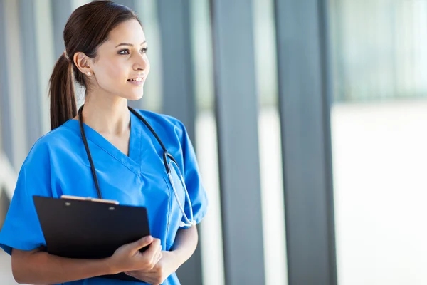 Beautiful young female medical intern looking outside window