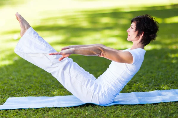Middle aged woman doing yoga pose outdoors