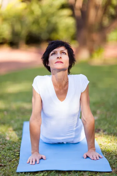 Middle aged woman doing yoga stretching outdoors