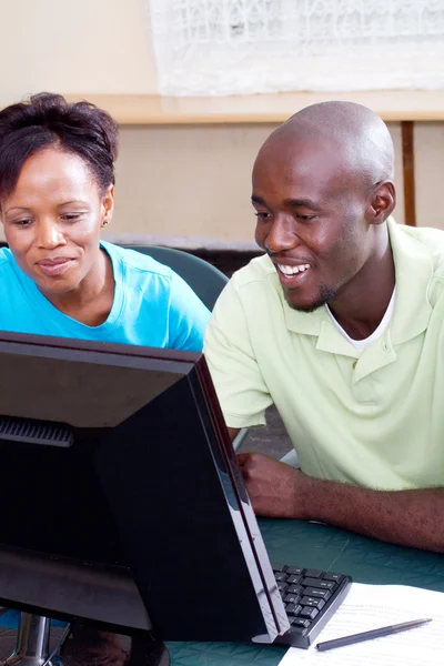 Two adult african students studying computer together