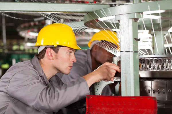 Two textile weaving machine mechanics repairing loom