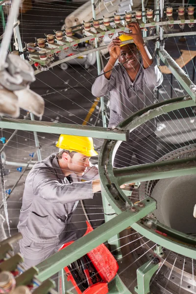 Two textile weaving machine mechanics fixing loom