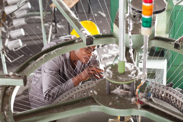 African american textile factory technician repairing weving loom