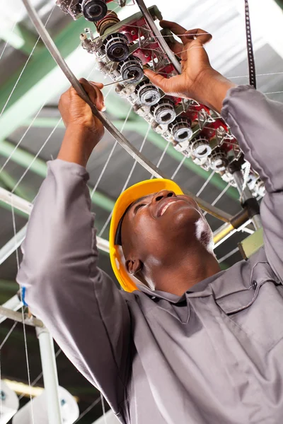 African american textile industrial technician repairing weaving machine