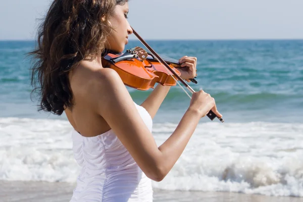 Young pretty woman playing violin on beach