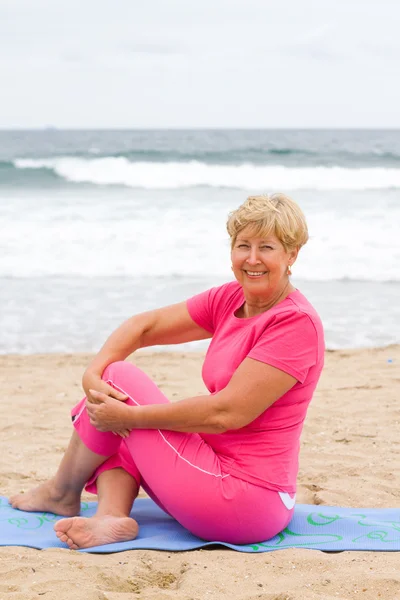 Happy senior woman doing fitness on beach