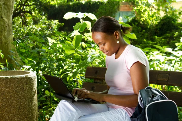 Female african college student using laptop outdoors