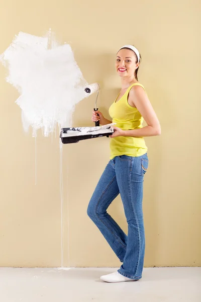 Happy young woman painting the wall at home