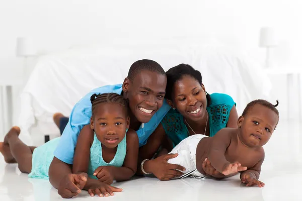 Happy african american family lying on bedroom floor