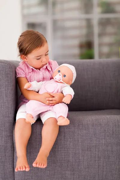 Cute little girl playing with doll at home