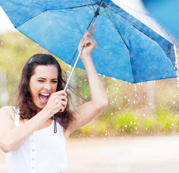 Playful young woman holding umbrella in the rain