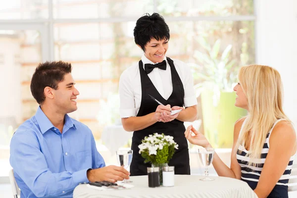 Friendly middle aged waitress taking order from customer in restaurant