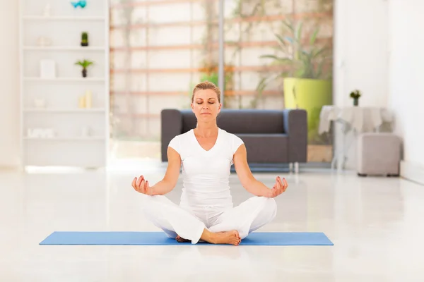 Middle aged woman doing yoga meditation at home