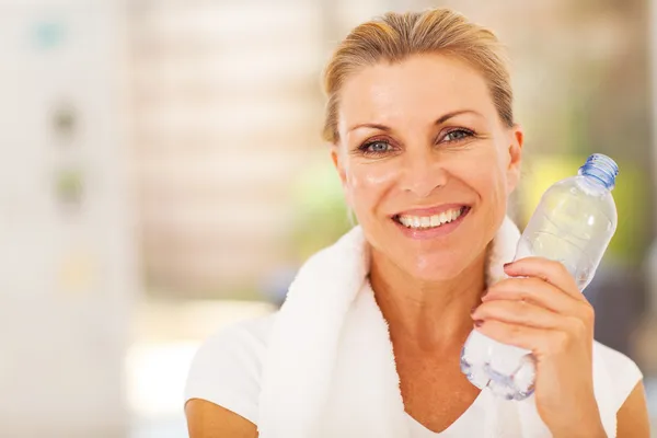 Healthy senior woman with exercise towel and water