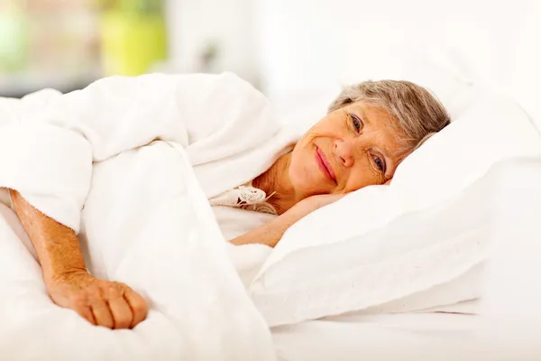 Happy senior woman sleeping on bed — Stock Photo #19563897