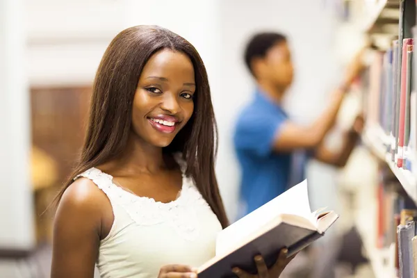Female african american university student reading book in library