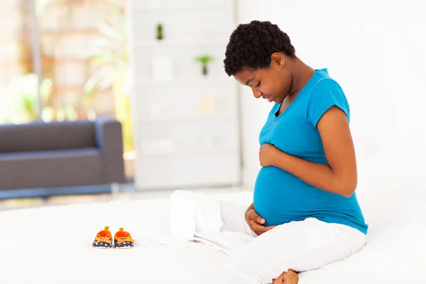 Pregnant african american woman sitting on bed