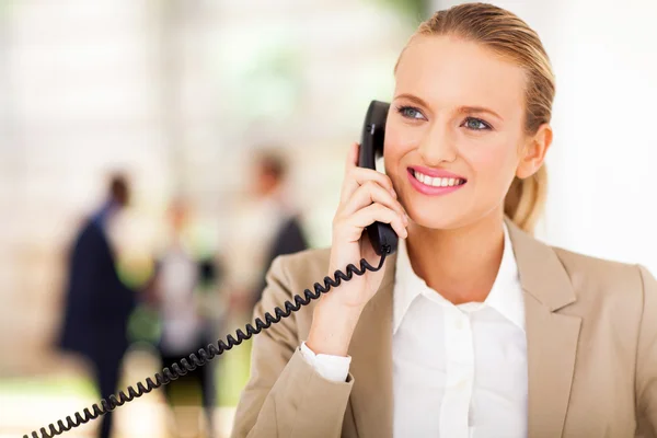 Happy female office worker talking on landline phone