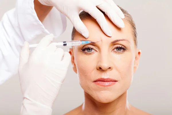 Cosmetic surgeon giving face lifting injection
