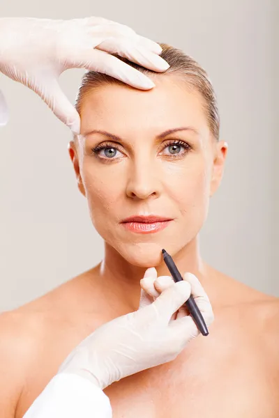Cosmetic surgeon marking mid age woman