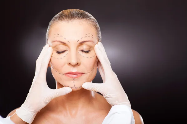 Plastic surgeon checking middle aged woman face