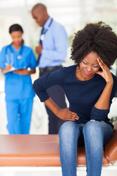 African ill woman sitting in doctors room