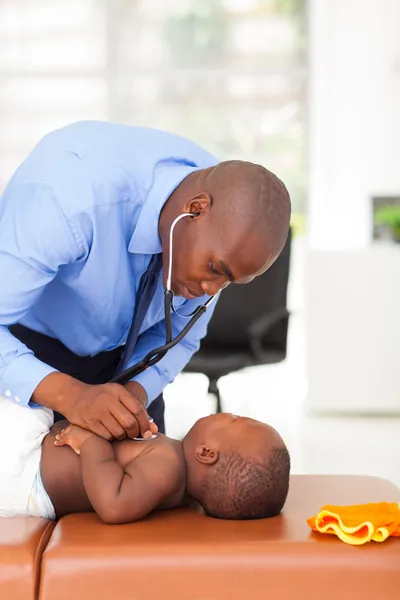 African doctor examining baby boy