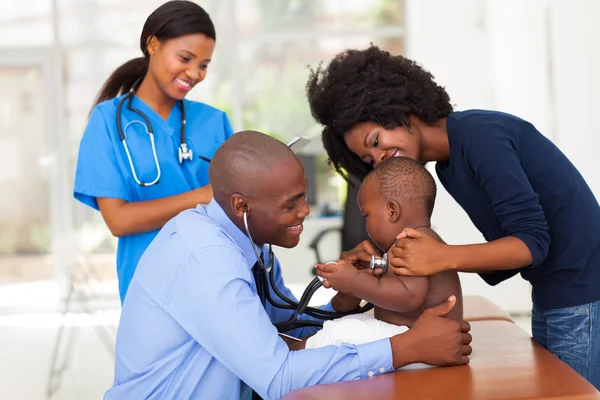 African mother and her son in doctor's office with doctor and nu