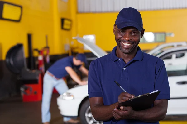 African american male vehicle mechanic writing report