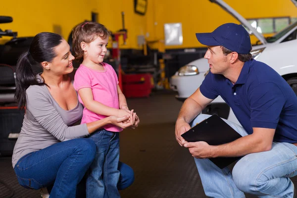 Friendly auto technician talking to customer\'s daughter