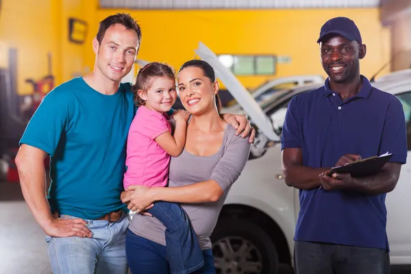 Happy family in garage with auto mechanic