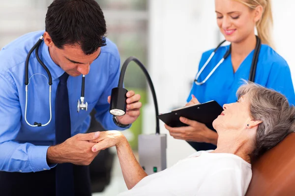 Dermatologist examining senior woman's skin