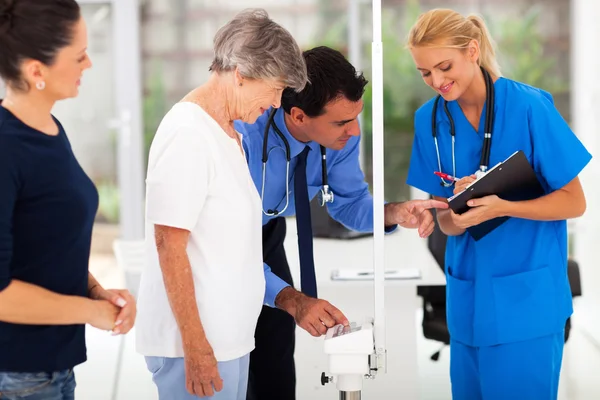 Medical doctor monitoring senior patient\'s weight