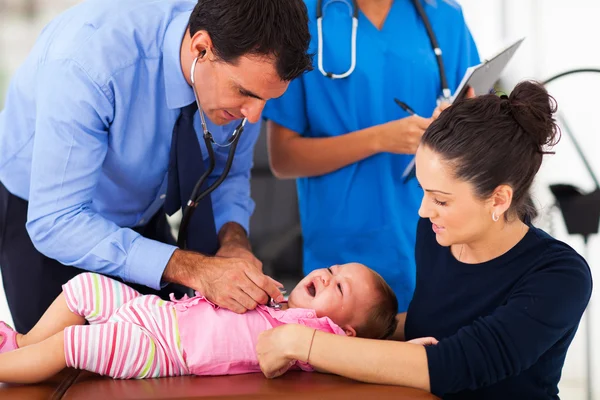 Pediatric doctor examining a crying baby