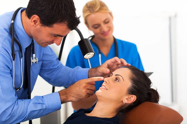 Ophthalmologist examining young woman's eye