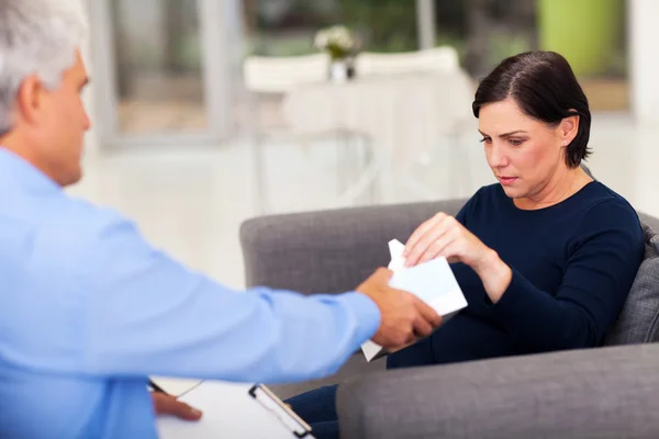 Therapist handing tissue to an upset middle aged patient
