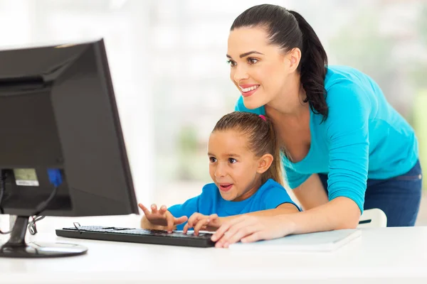 Happy mother teaching daughter computer