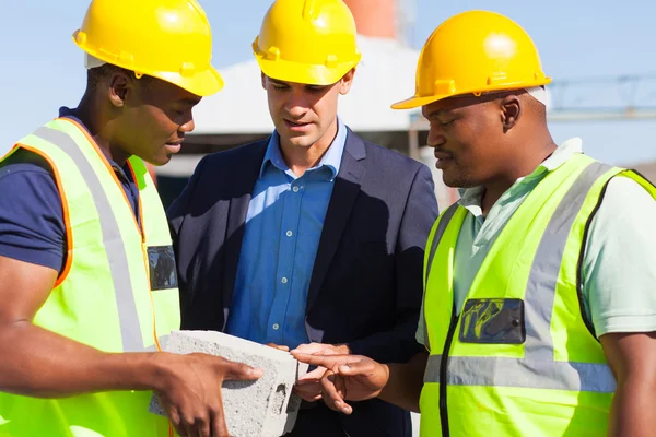 Manager and construction workers examining a brick