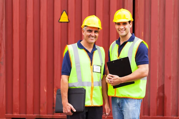 Shipping company workers standing in front of containers