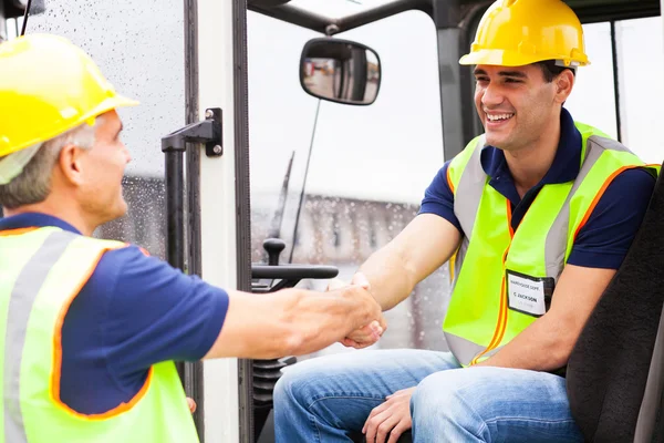 Warehouse forklift drivers handshaking