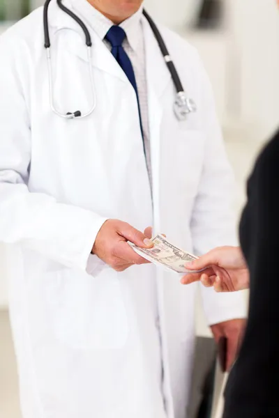 Male doctor receiving money from a patient