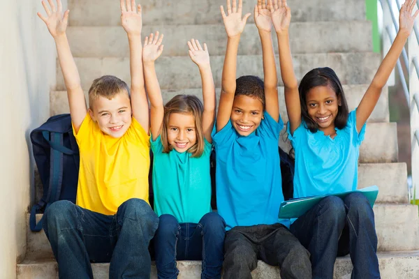 Happy primary students with hands raised