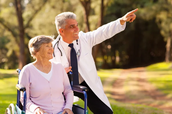 Friendly medical doctor and senior patient outdoors for a walk